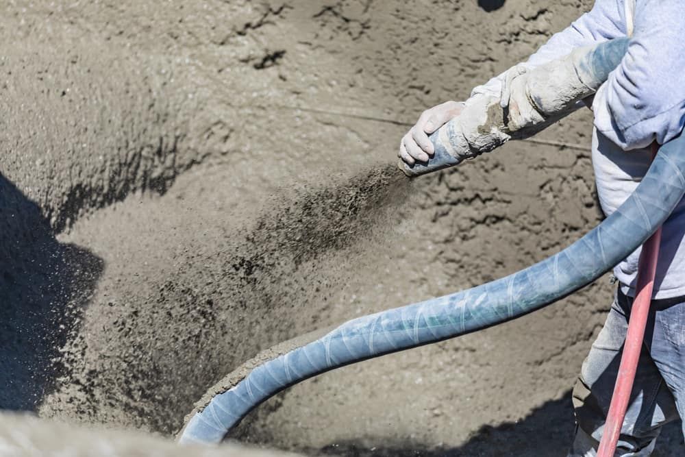 Person Spraying Concrete From a Hose Into a Dug-out Area — Clearspan Builders In Braidwood, NSW