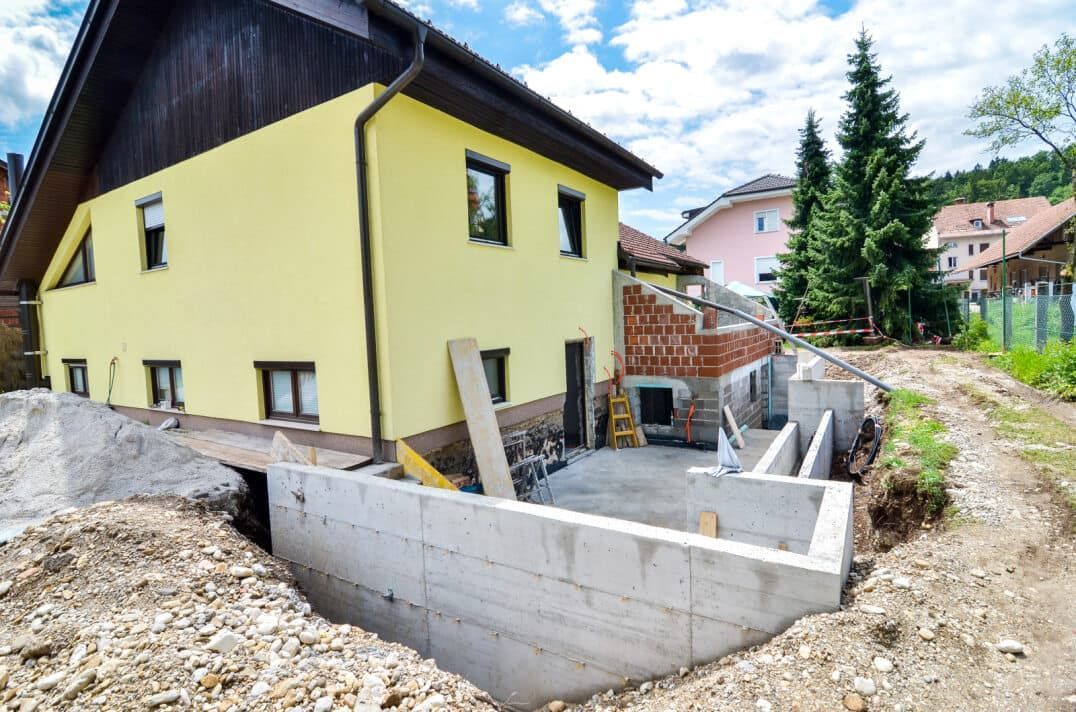 Construction of a Concrete Foundation Next to a Yellow House — Clearspan Builders In Yass, NSW