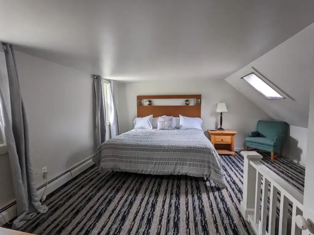 A hotel room with a king size bed and a chair.