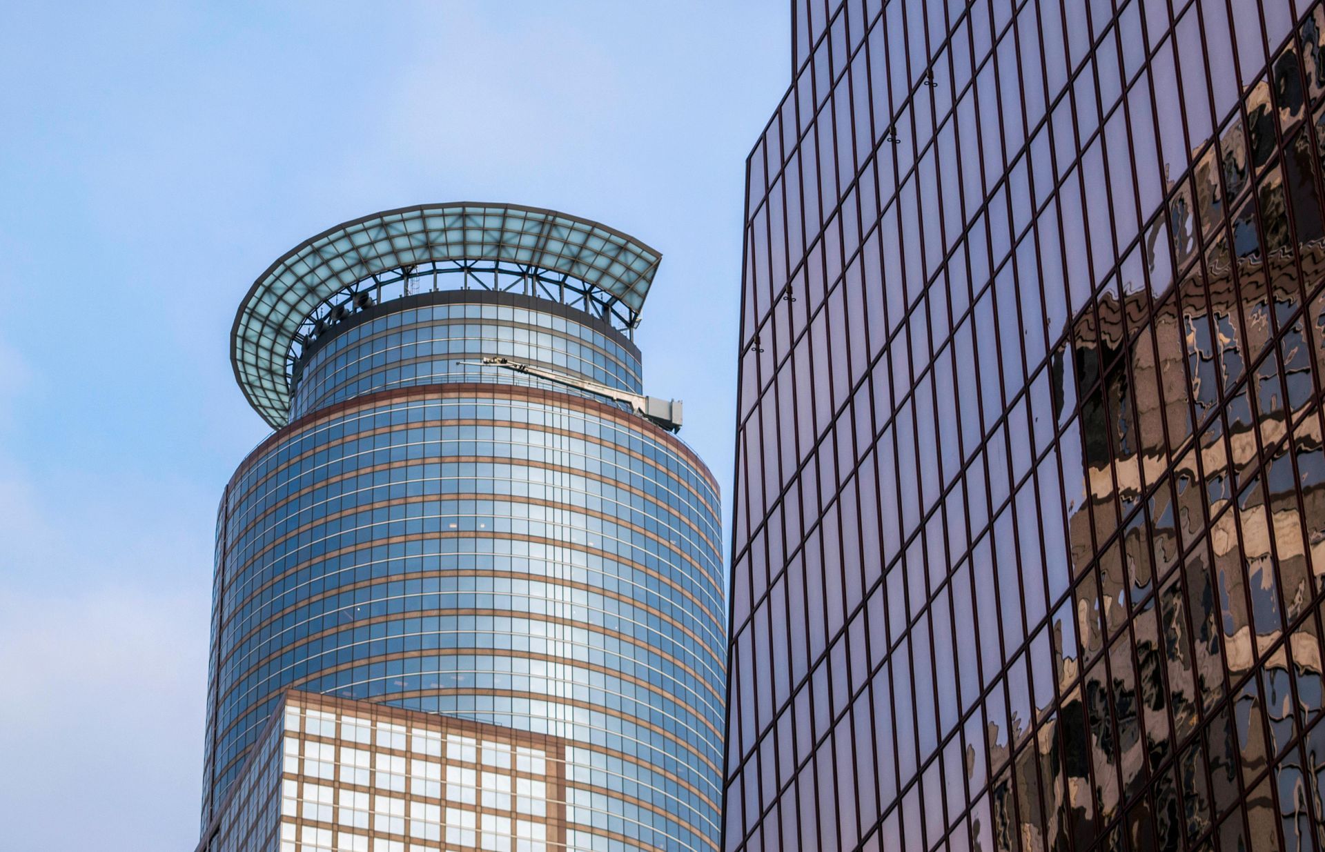 Two modern skyscrapers with glass facades against a blue sky.