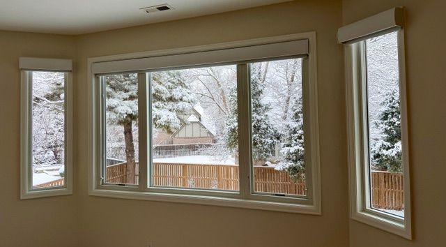 Three windows with snowy outdoor view; tan walls.