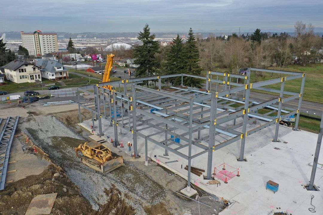 An aerial view of a construction site showing the steel framework of a building in progress.