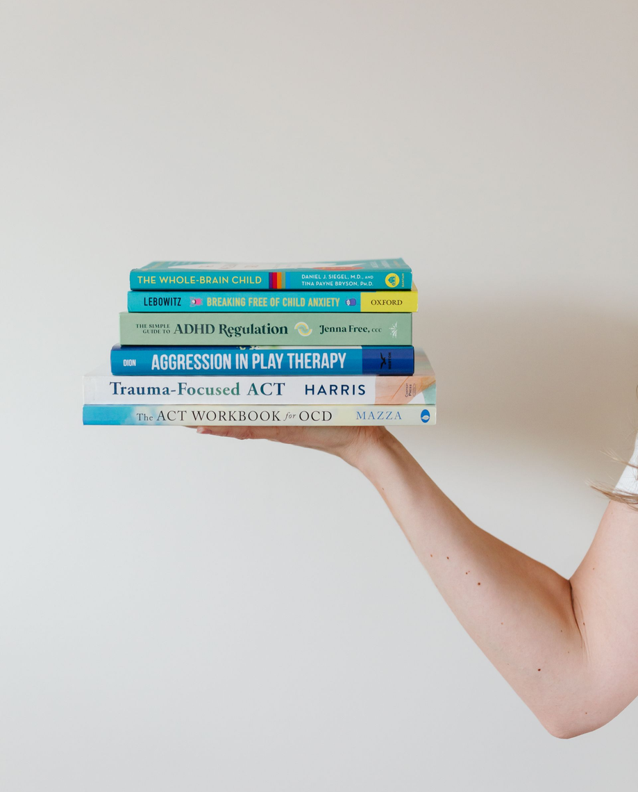 Stack of colorful books balanced on an outstretched arm against a plain background