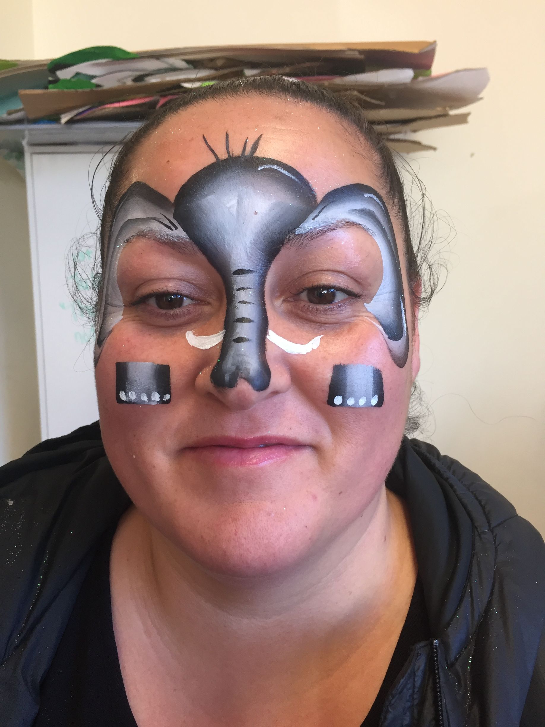 Woman with elephant face paint; grey, black, and white design.