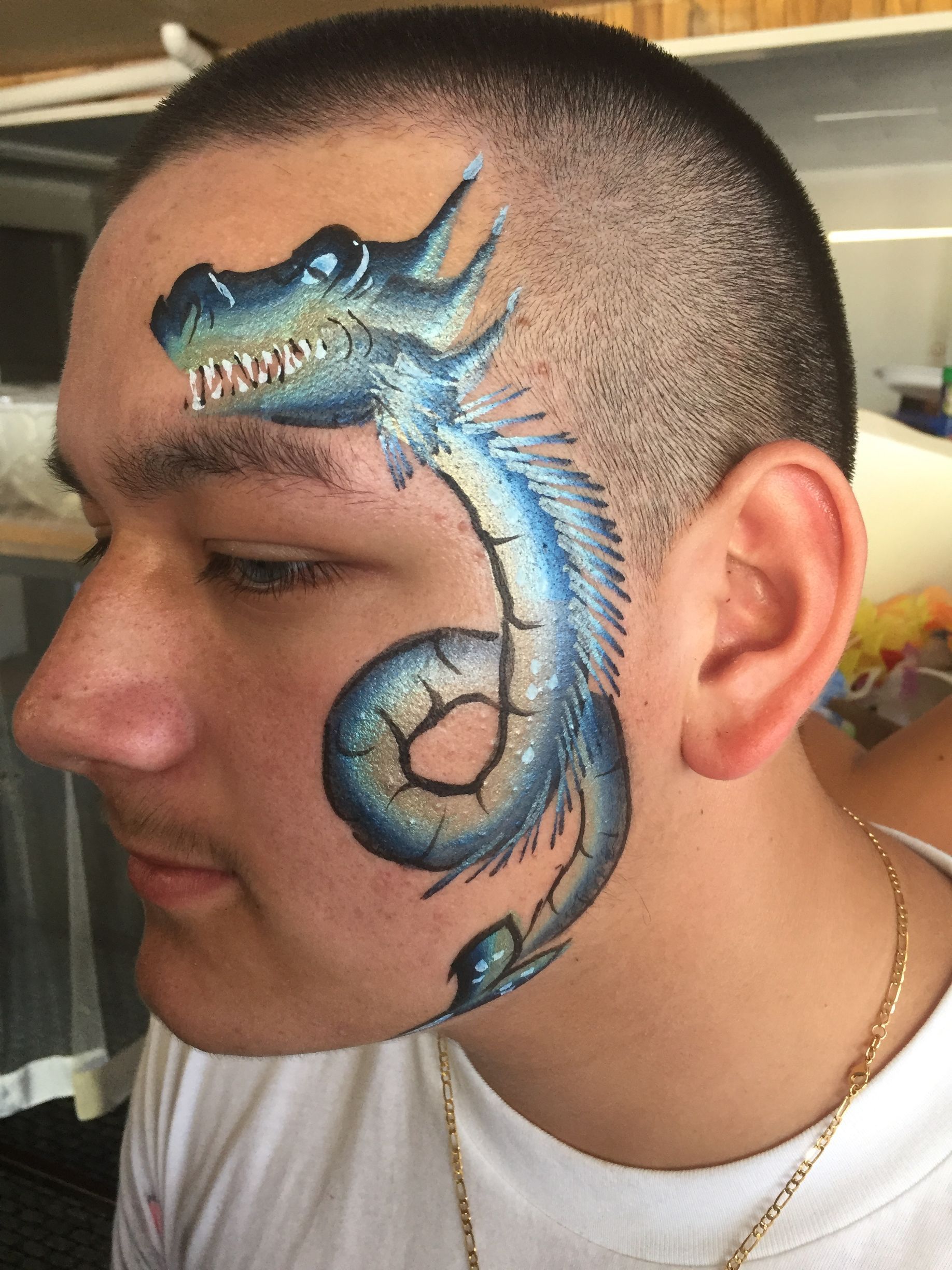 Man with blue dragon face paint on his face.
