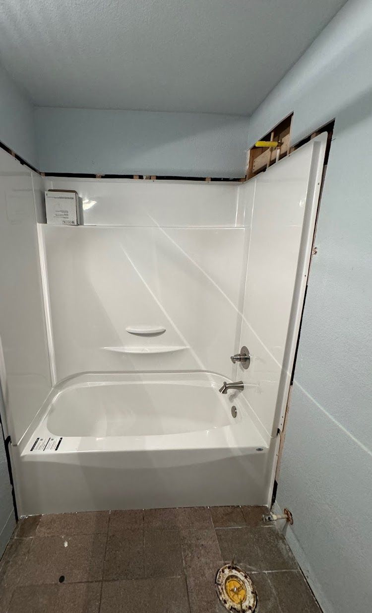 Prestige Plumbing LLC- a bathroom with a bathtub and a shower stall.