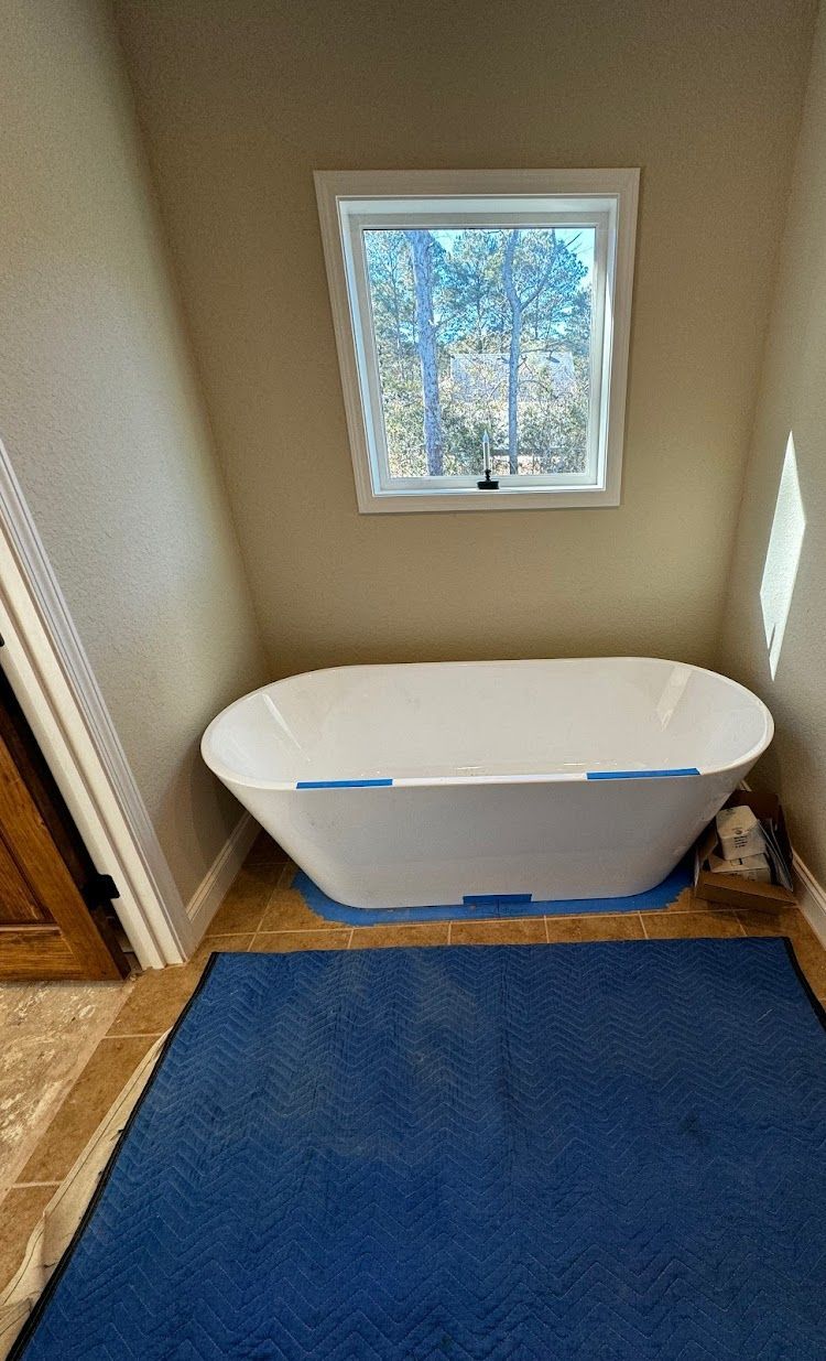 Prestige Plumbing LLC- a bathtub is sitting in a bathroom next to a window.