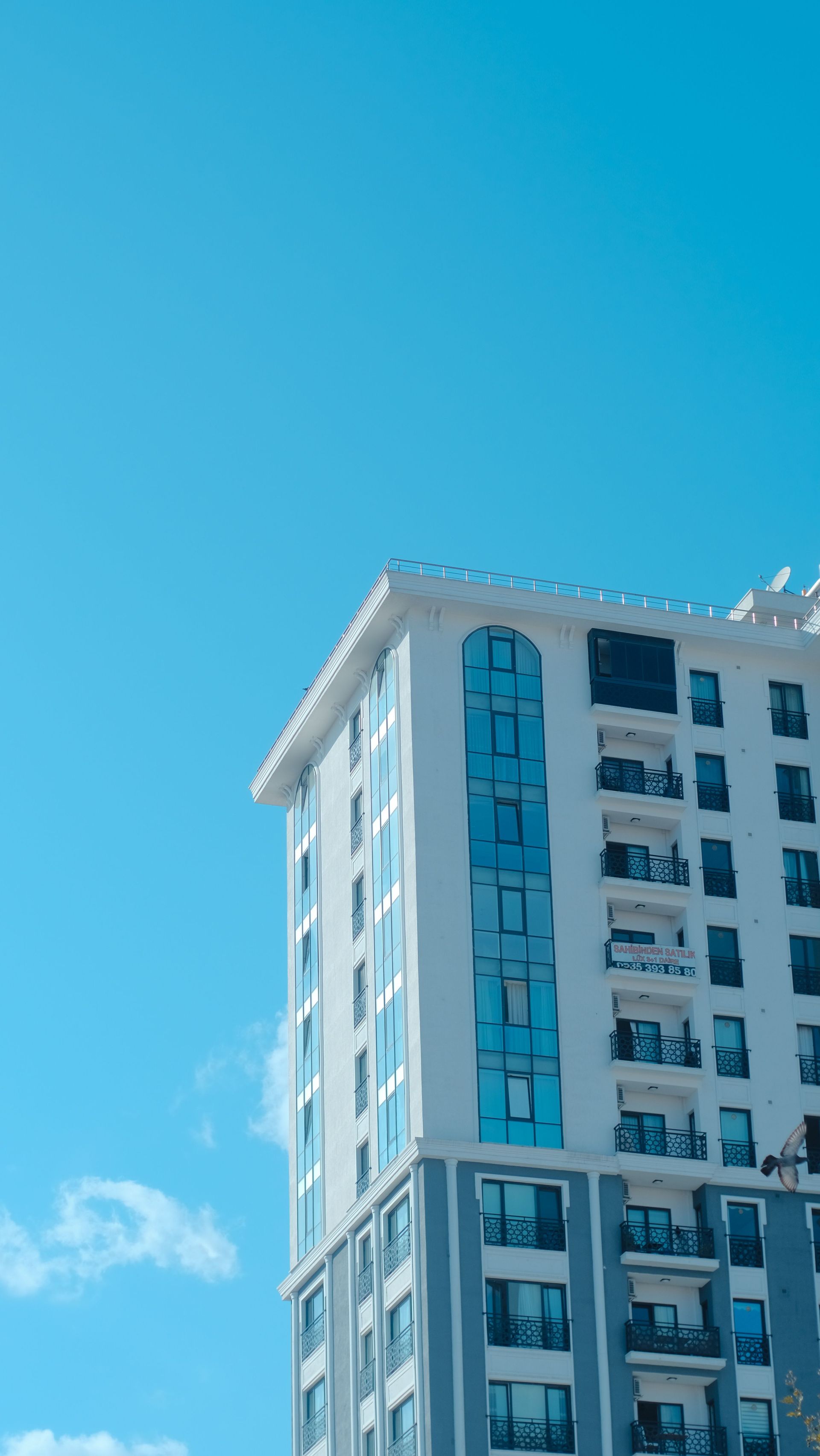Tall white building with blue windows against a clear bright blue sky