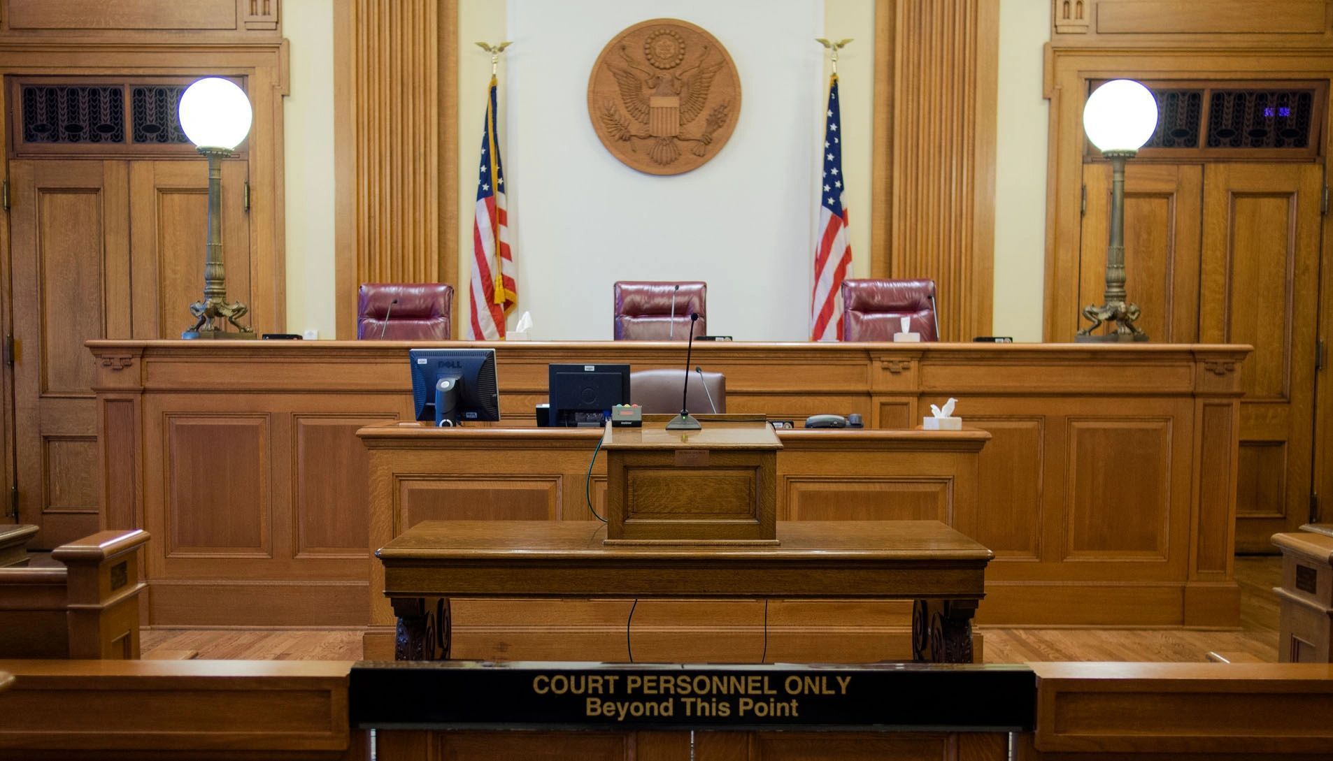 A judge 's bench in a courtroom with american flags on the wall.