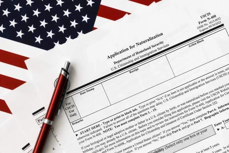 A pen is sitting on top of a form with an american flag in the background.