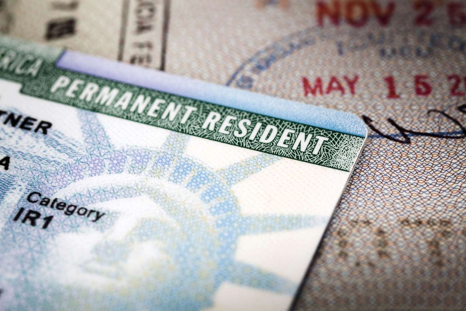 A permanent resident visa is sitting on top of a passport.