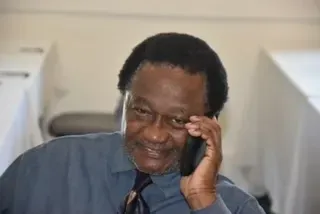 Man smiling while holding a phone to his ear in a booth-lined room