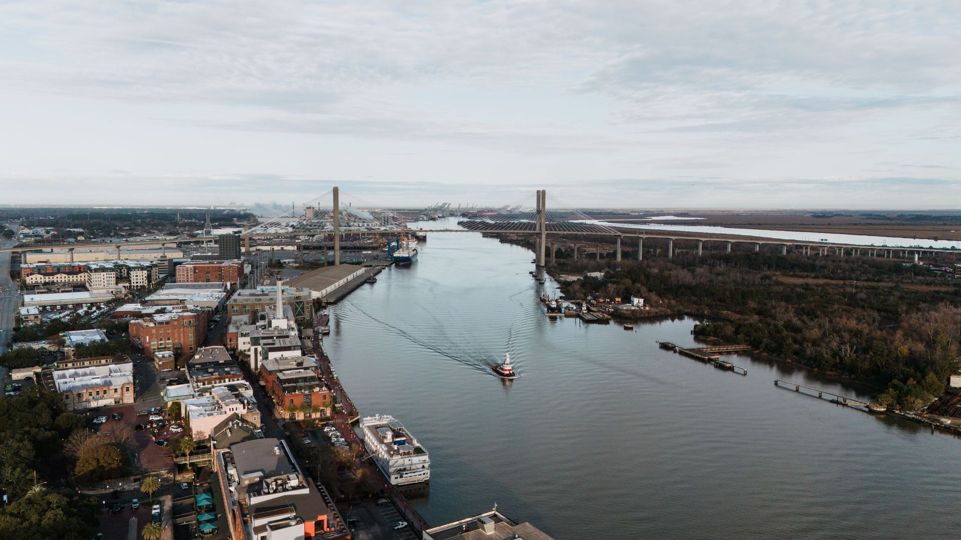Aerial view of a river city with two bridges, boats, and buildings lining both banks