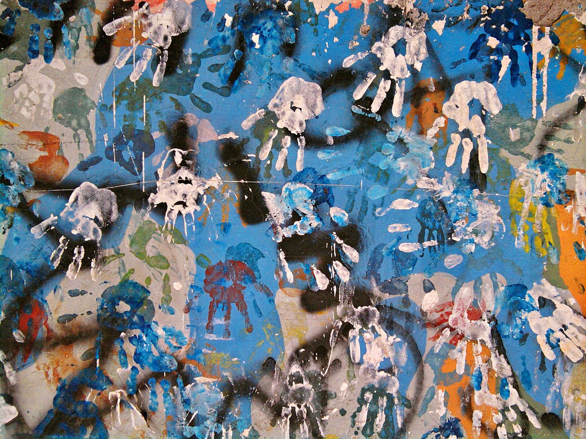 Abstract blue and tan paint splatters with layered drips and textured brushstrokes