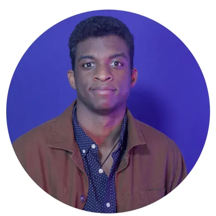 Portrait of a person against a blue circular background, wearing a brown jacket and navy shirt.