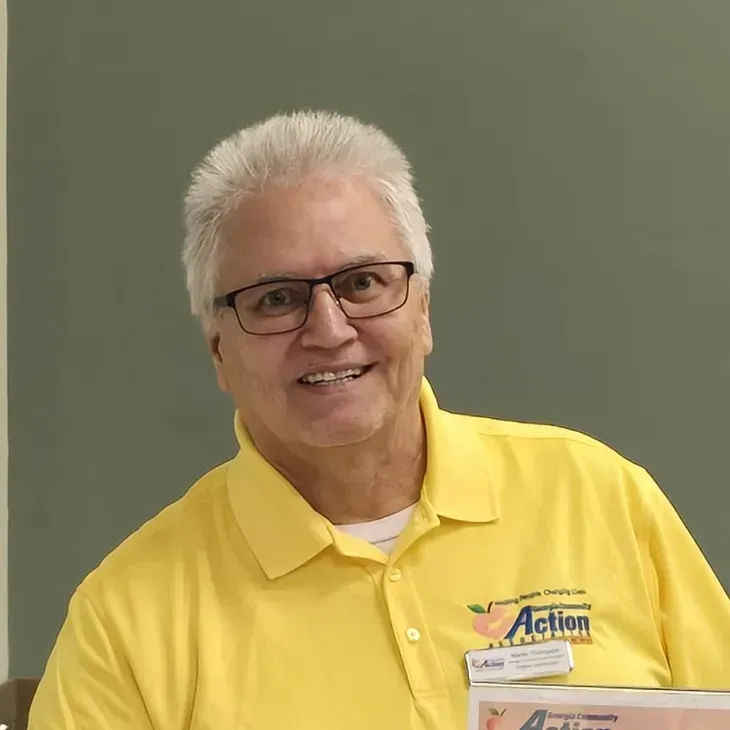 Man in yellow polo shirt smiling against a plain gray background
