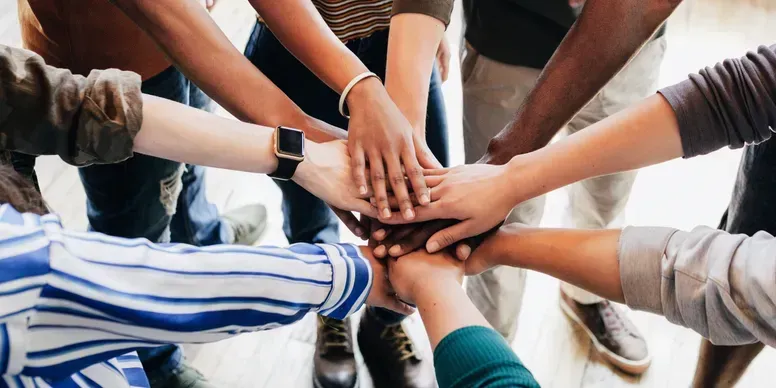 Hands stacked together in a team huddle on an outdoor court