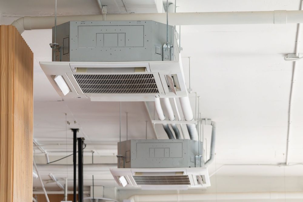 Ceiling-mounted HVAC units and vents in a white industrial interior