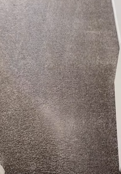 A close up of a gray carpet with a white door in the background.
