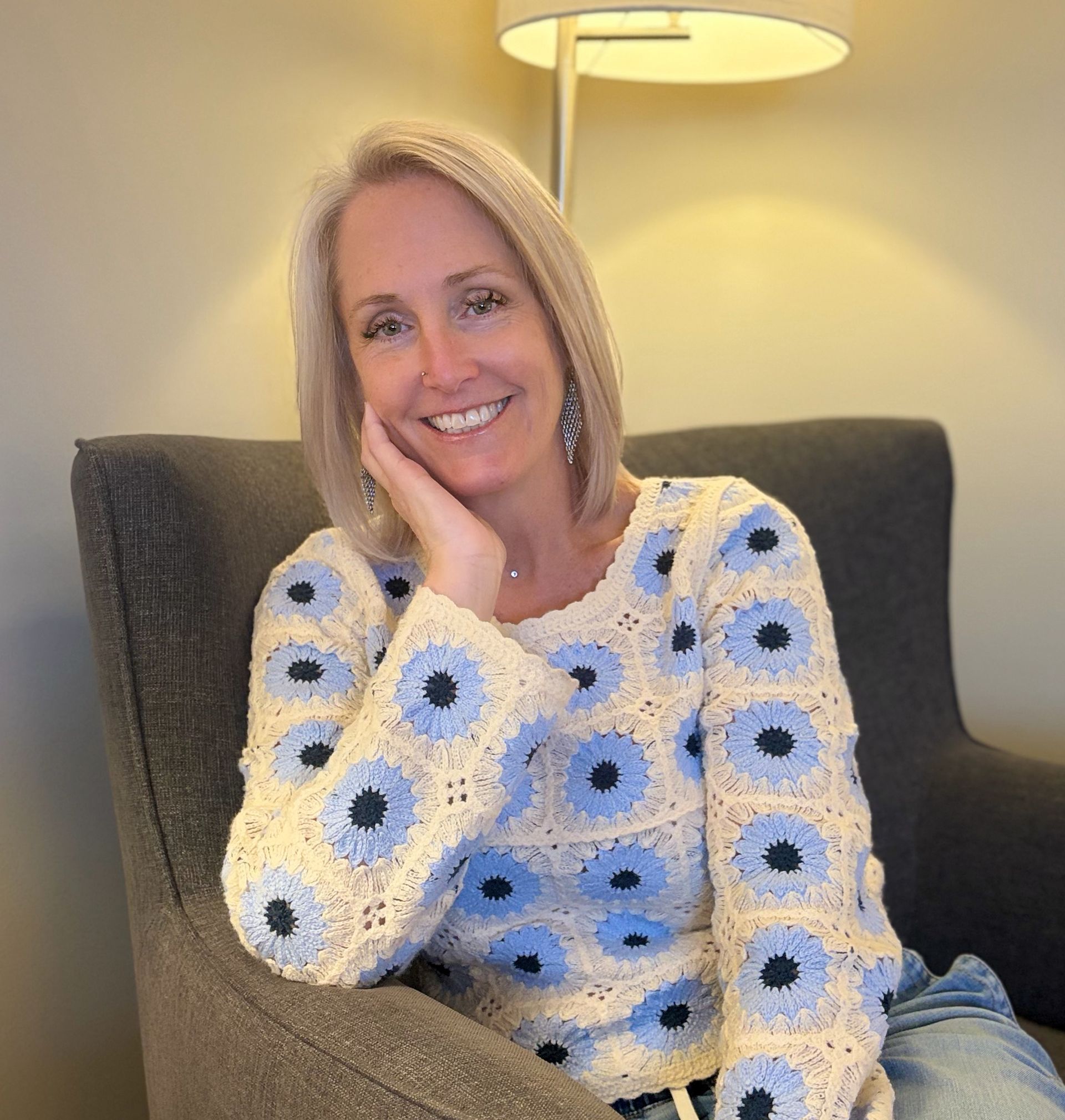 Smiling blonde woman in a white button-down shirt against a light background