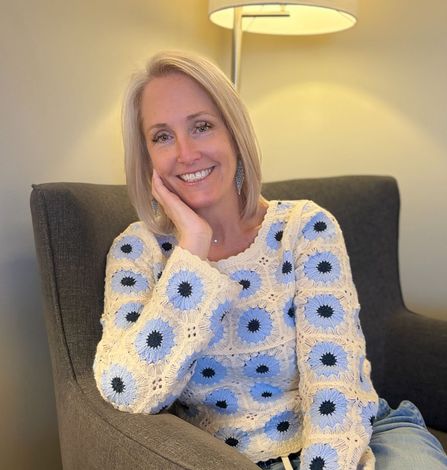 A woman in a brown jacket and white shirt is smiling in front of a river. Terri Ward
