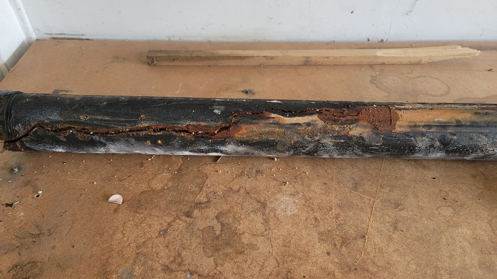 Slab Leak Detection & Repair Charred wooden beam along a wall, showing heavy burn damage and soot.