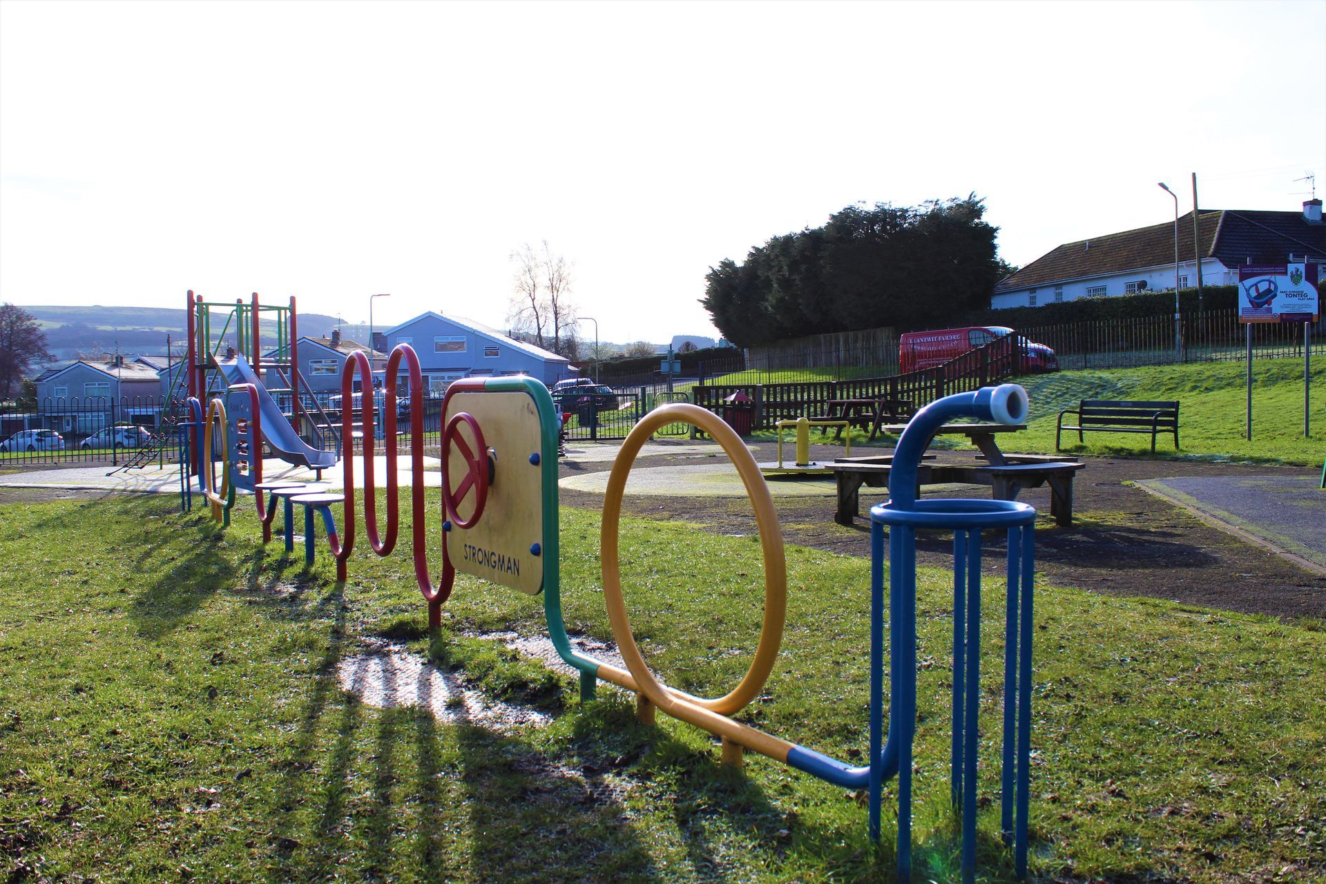 Playground equipment in a grassy park, with colorful structures and picnic tables visible.