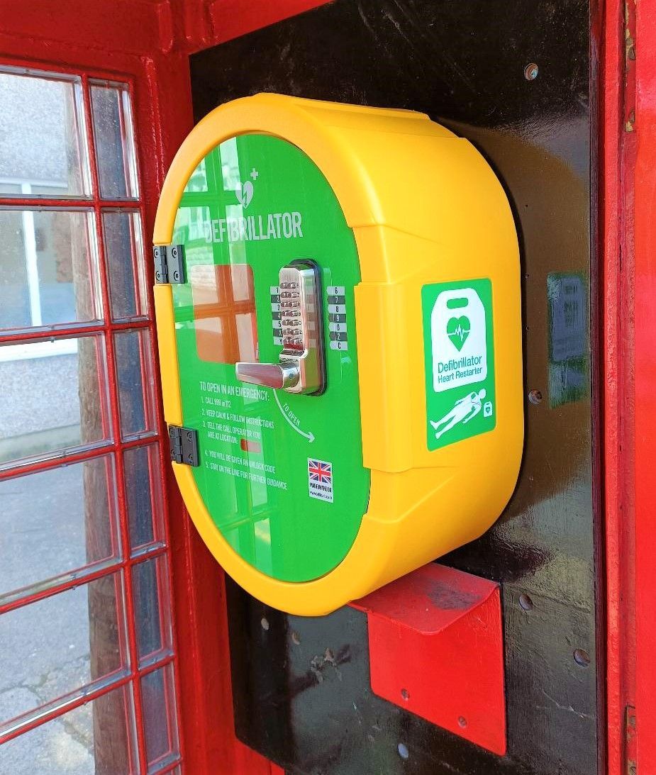 Yellow defibrillator in a red phone booth. Green and white graphics with instructions.