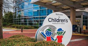 Children’s Hospital sign with cartoon mascots outside a modern glass building
