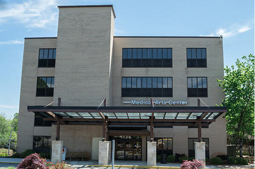 Modern medical center building with glass entrance and covered walkway on a sunny day