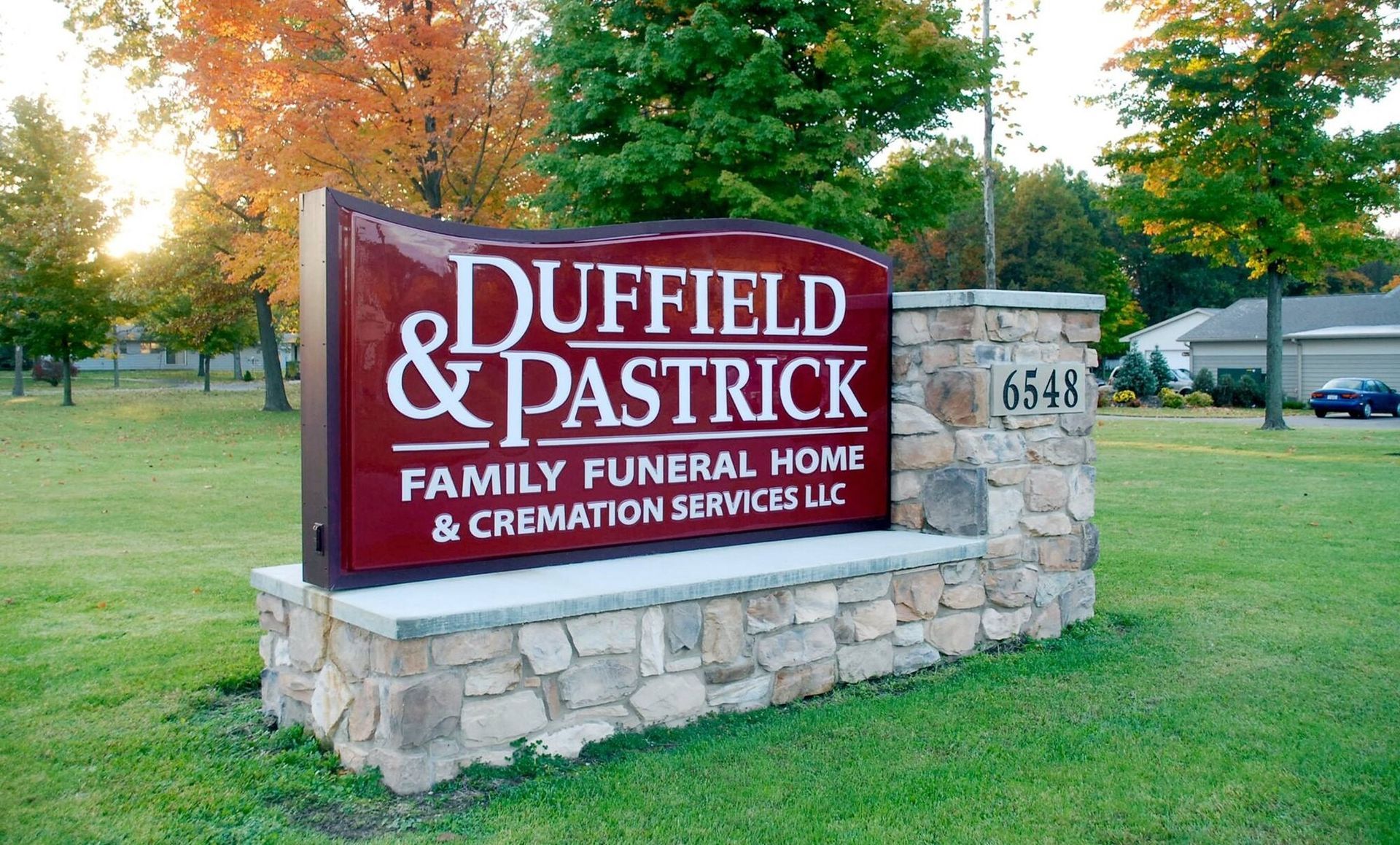 Duffield & Pastrick Family Funeral Home sign on a stone base by a grassy roadside