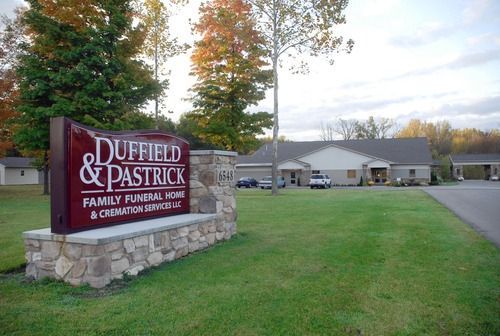 Duffield & Pastrick funeral home sign beside a suburban building and road in autumn