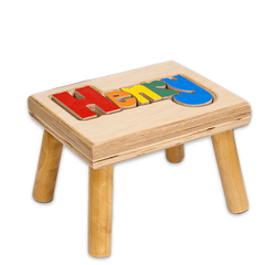 Wooden puzzle stool with colorful “Charlie” name letters on the seat. Custom from Hollow Woodworks