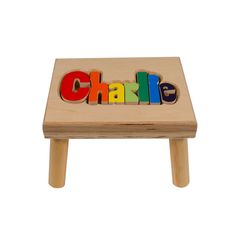 Wooden puzzle stool with colorful “Charlie” name letters on the seat. Custom from Hollow Woodworks