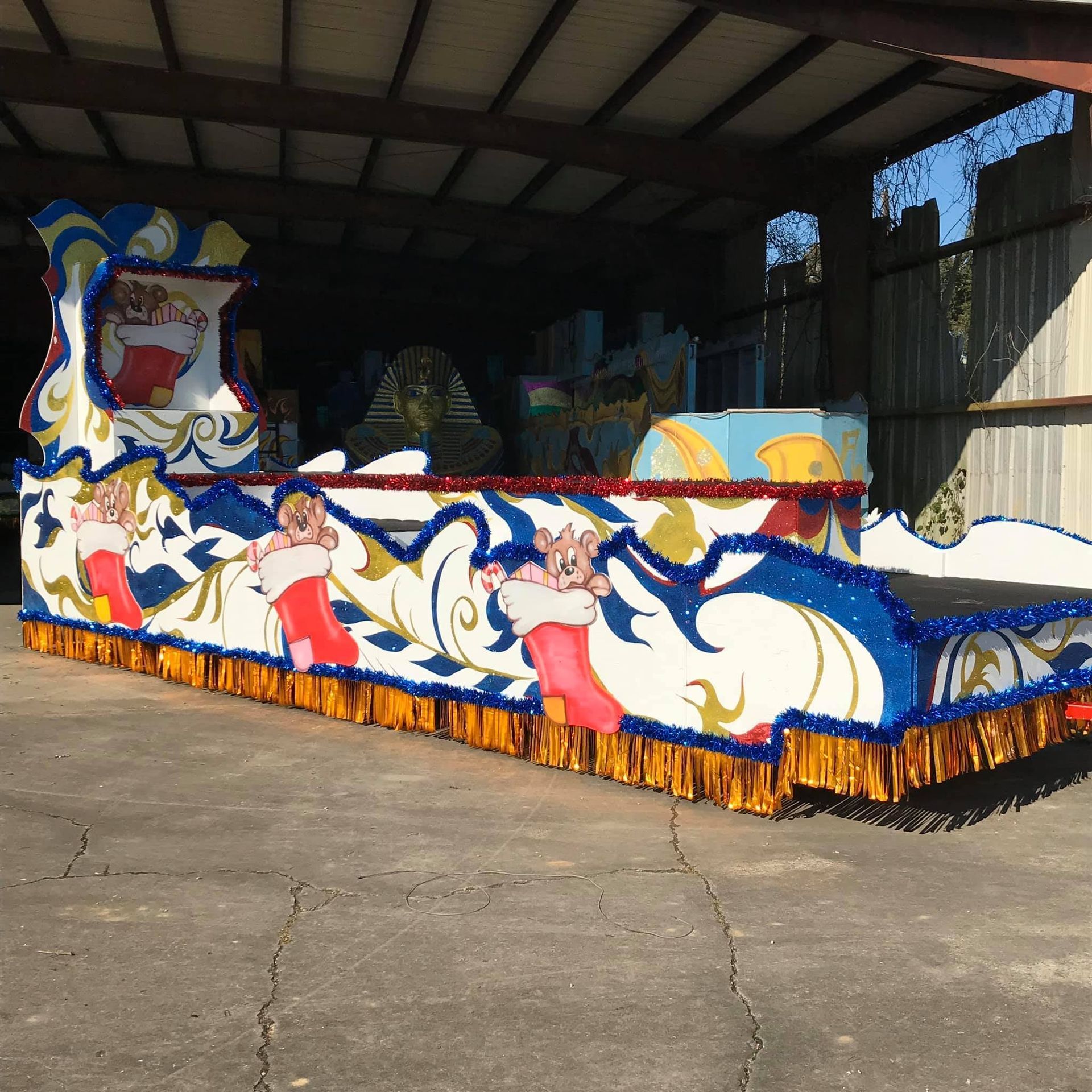 Holiday parade float with pigs in stockings, blue and white design with gold fringe.