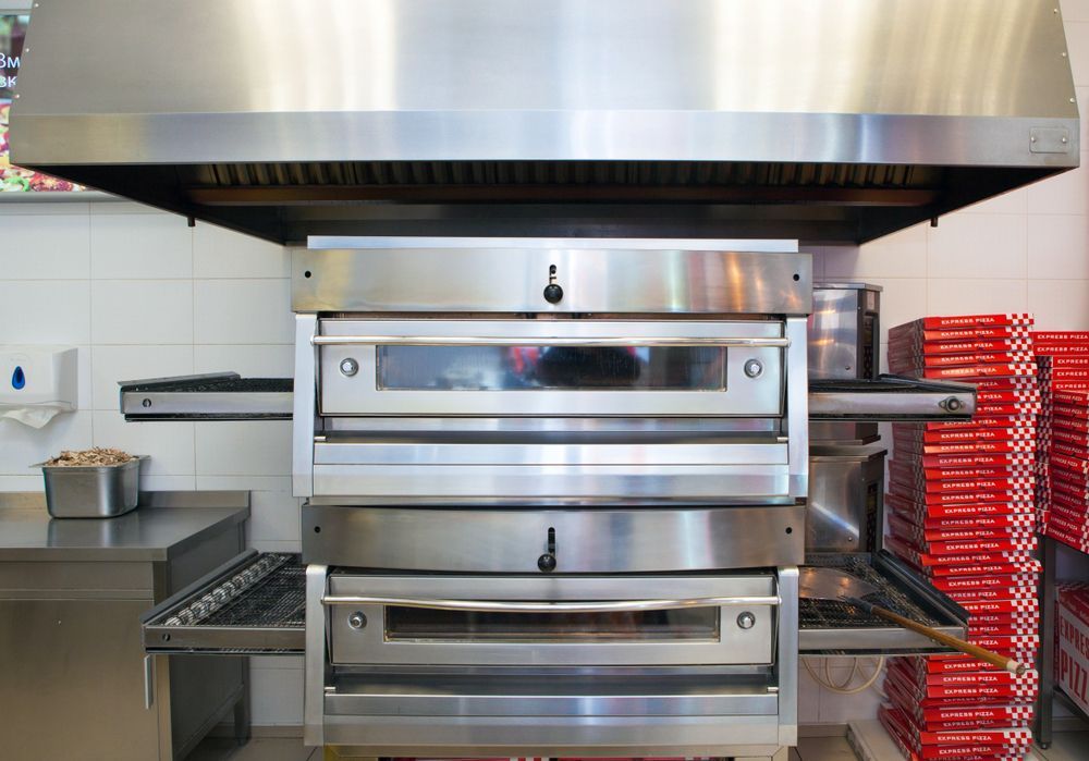 Pizza Oven With a Stainless Steel Hood in a Commercial Kitchen — Central Coast Commercial Kitchen Cleaning in Tuggerah, NSW
