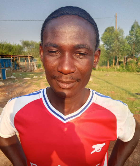 Man in Arsenal jersey smiles outdoors.