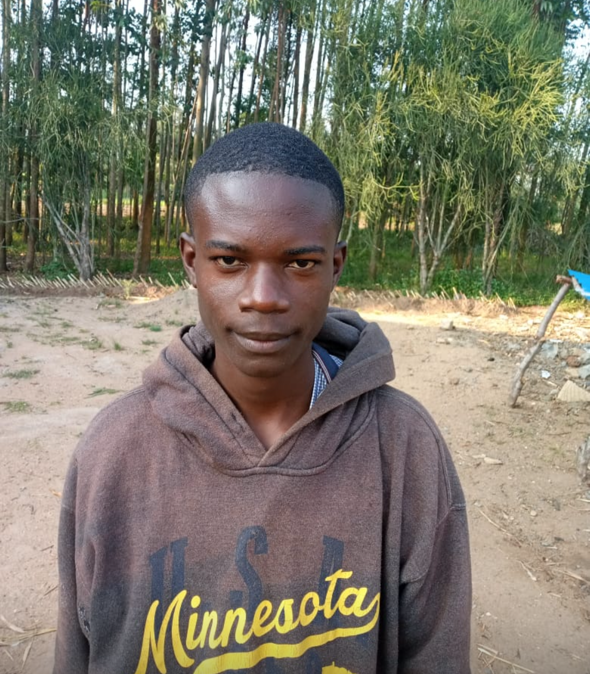 A young Black man in a brown Minnesota hoodie stands outside, looking at the camera.