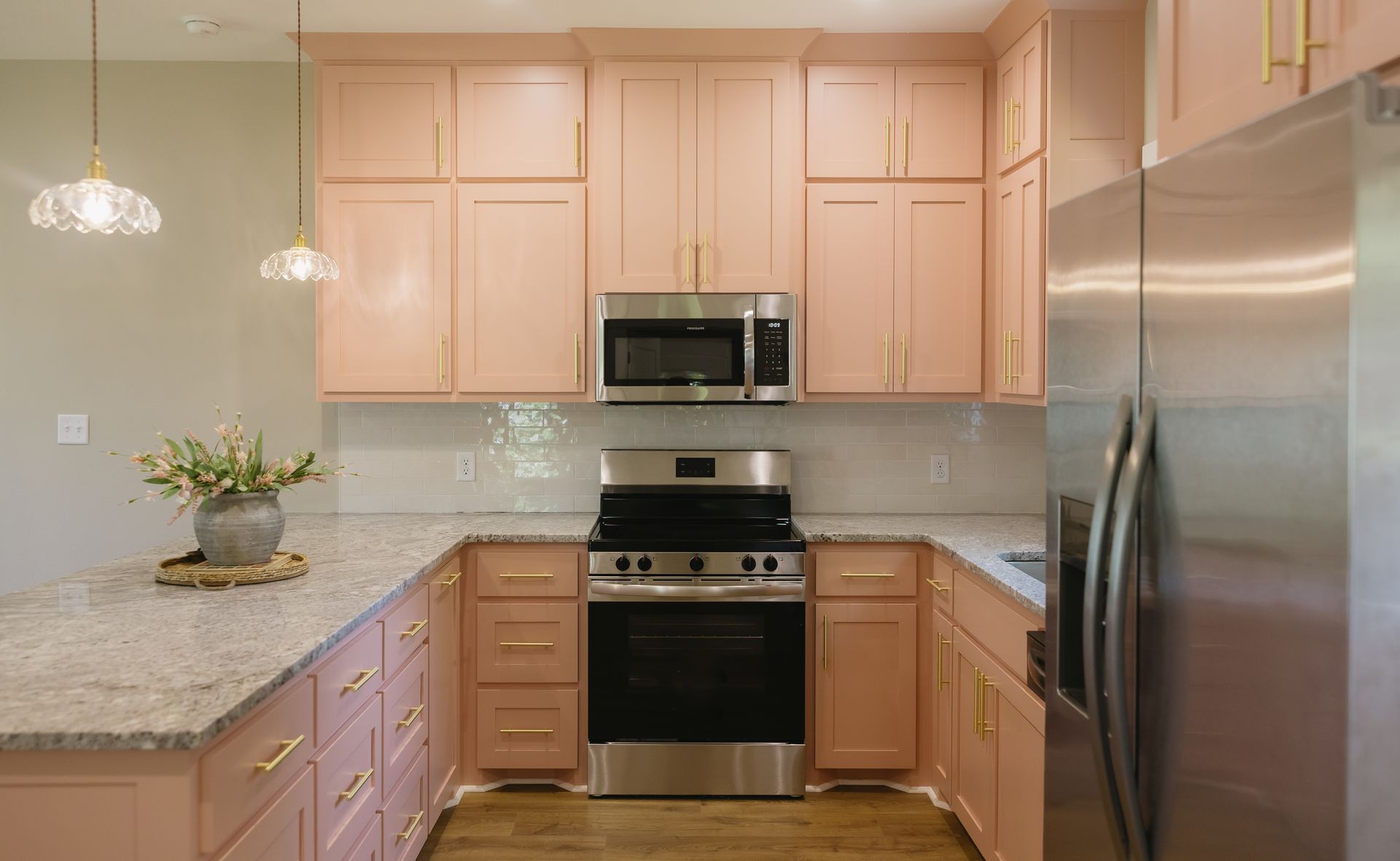 Modern kitchen with light wood cabinets, stainless steel appliances, and marble countertops