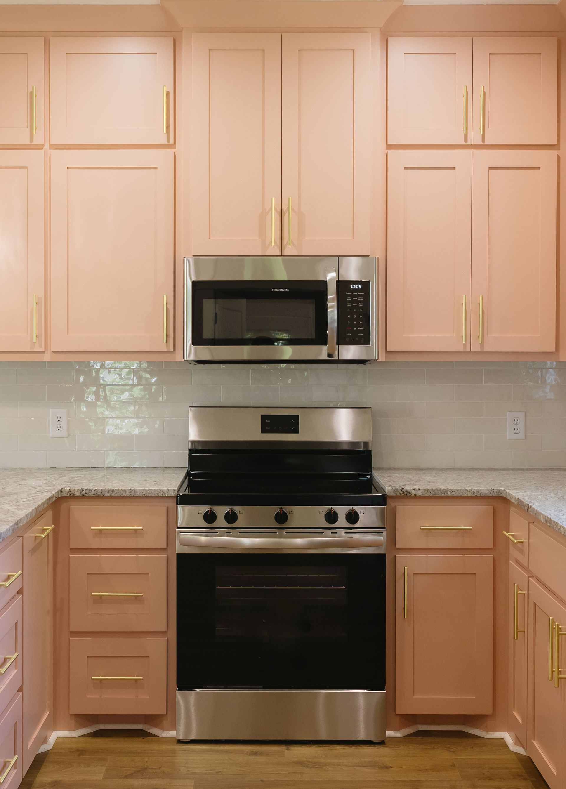 Modern kitchen with light wood cabinets, granite countertops, and stainless steel stove and microwave.