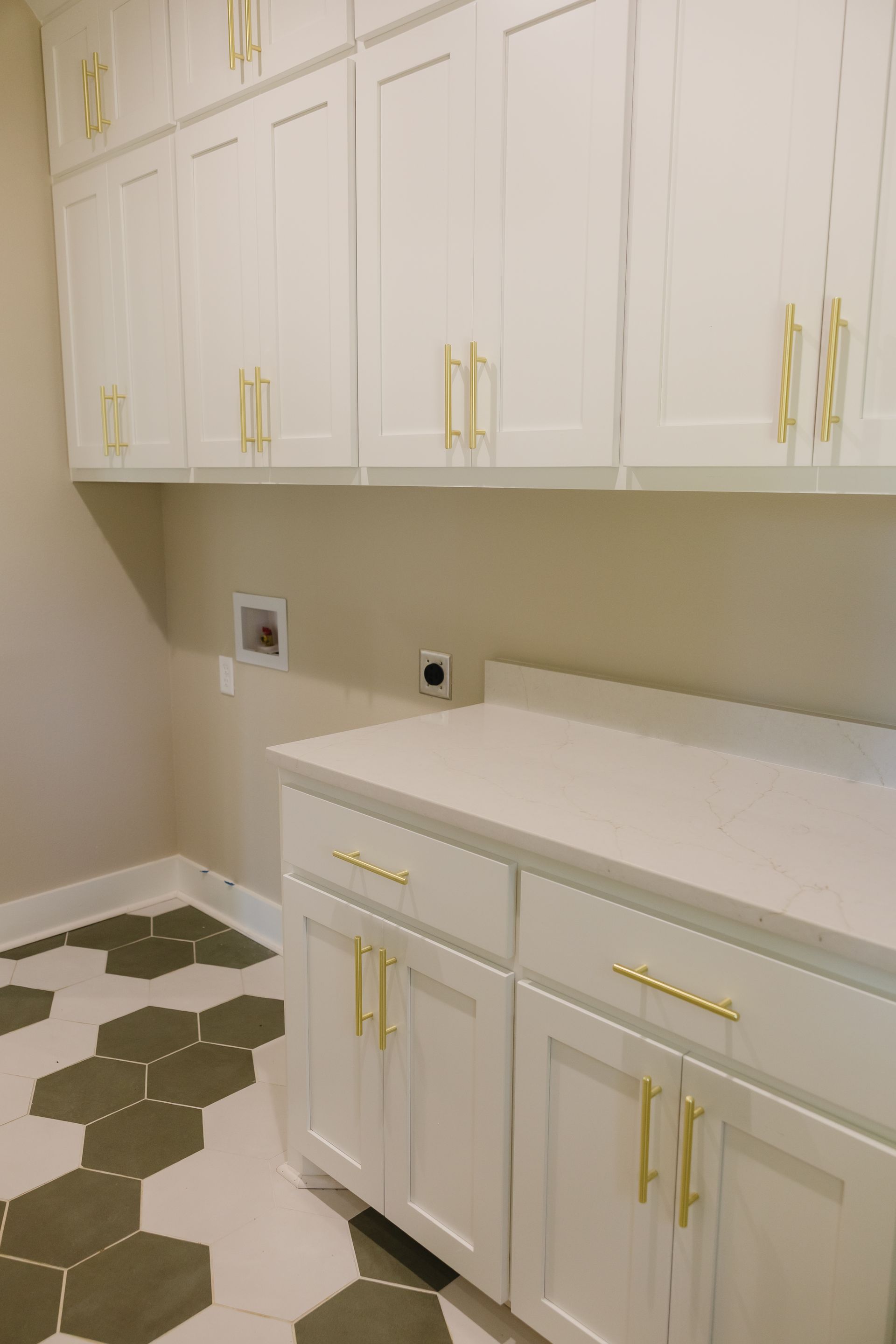 White cabinets and countertop in a bright kitchen with beige walls and hexagonal floor tiles