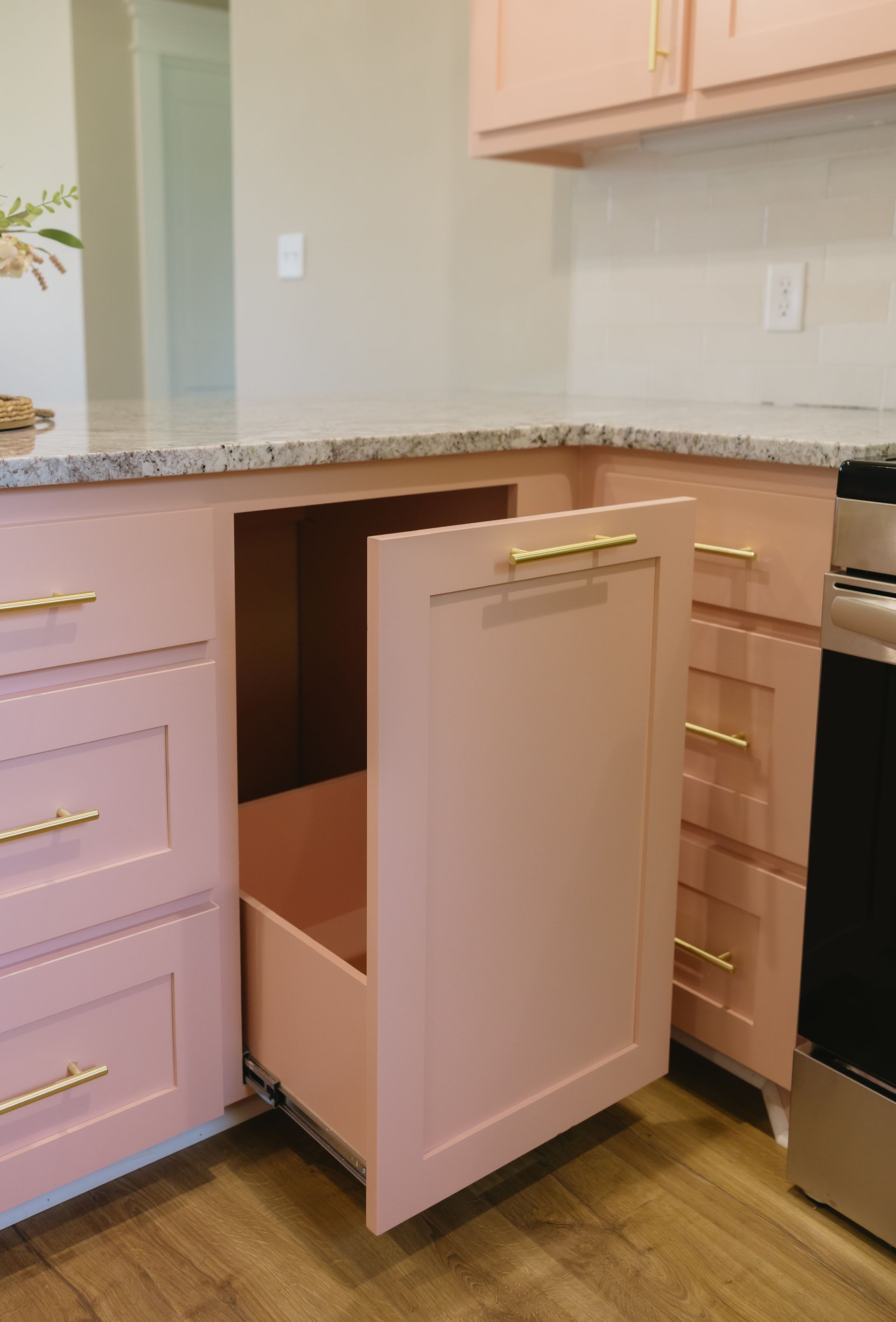 Kitchen cabinet pull-out trash bin open below countertop