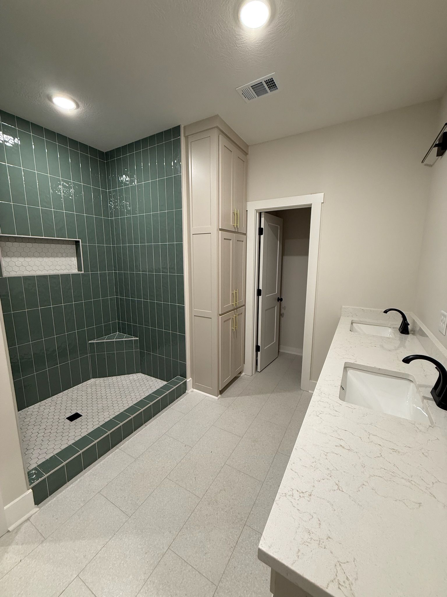 Accessible restroom with shower, sink counter, and green tiled accent wall