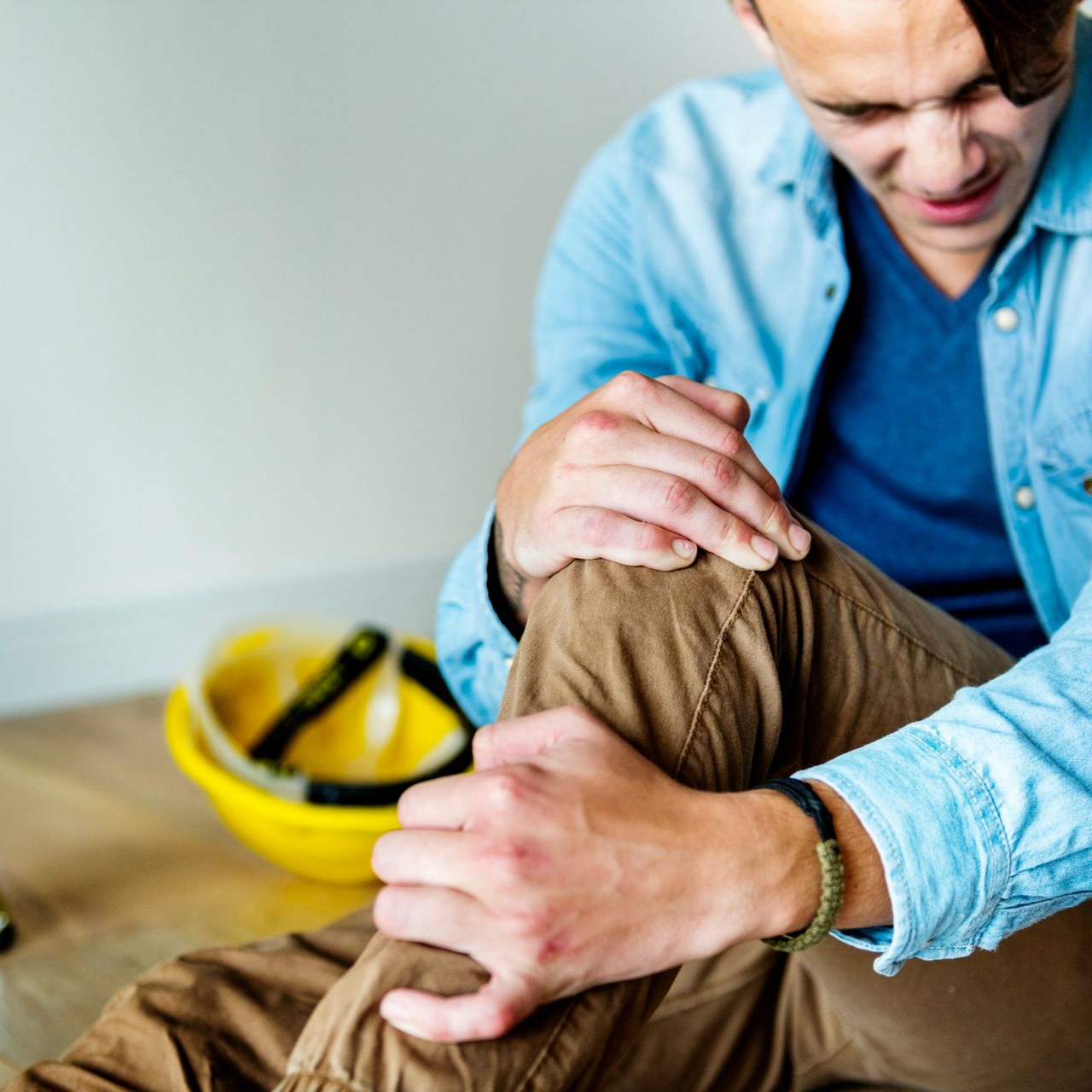 Man gently comforting an injured person’s head with a yellow first aid kit nearby