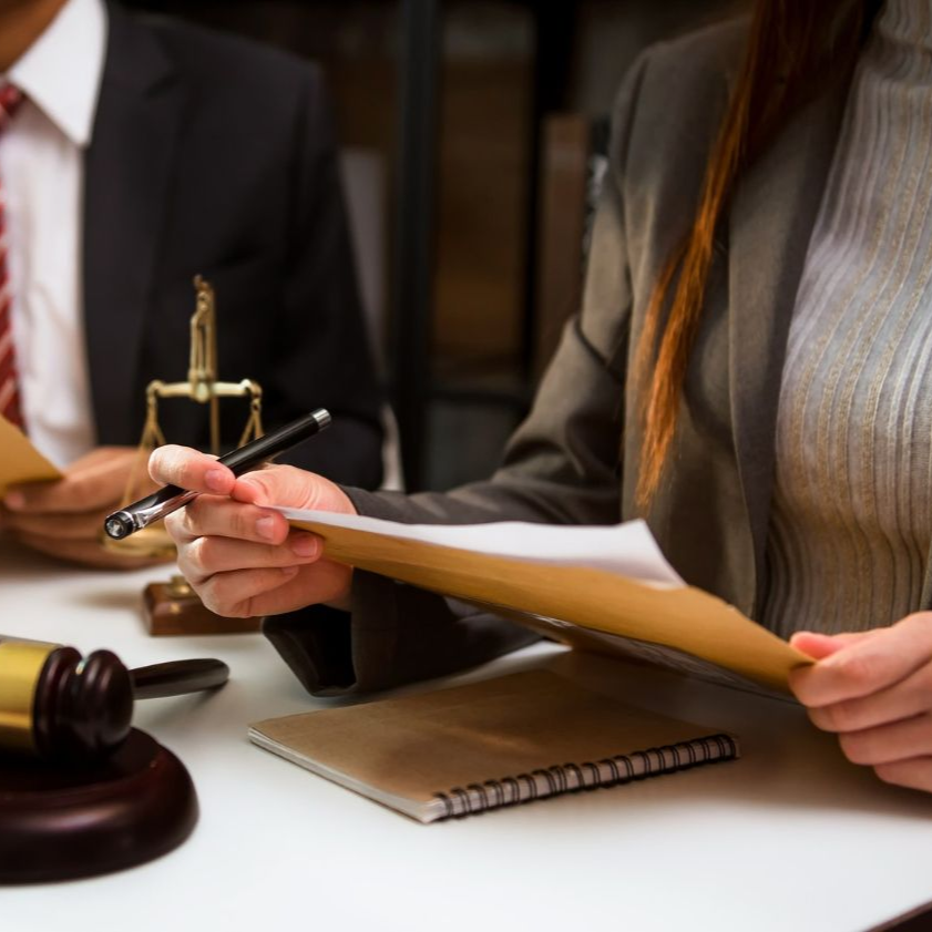 Lawyers reviewing documents at a desk with a gavel and scales in the background