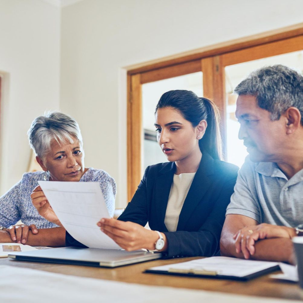 Three people reviewing a document together at a table in a bright office