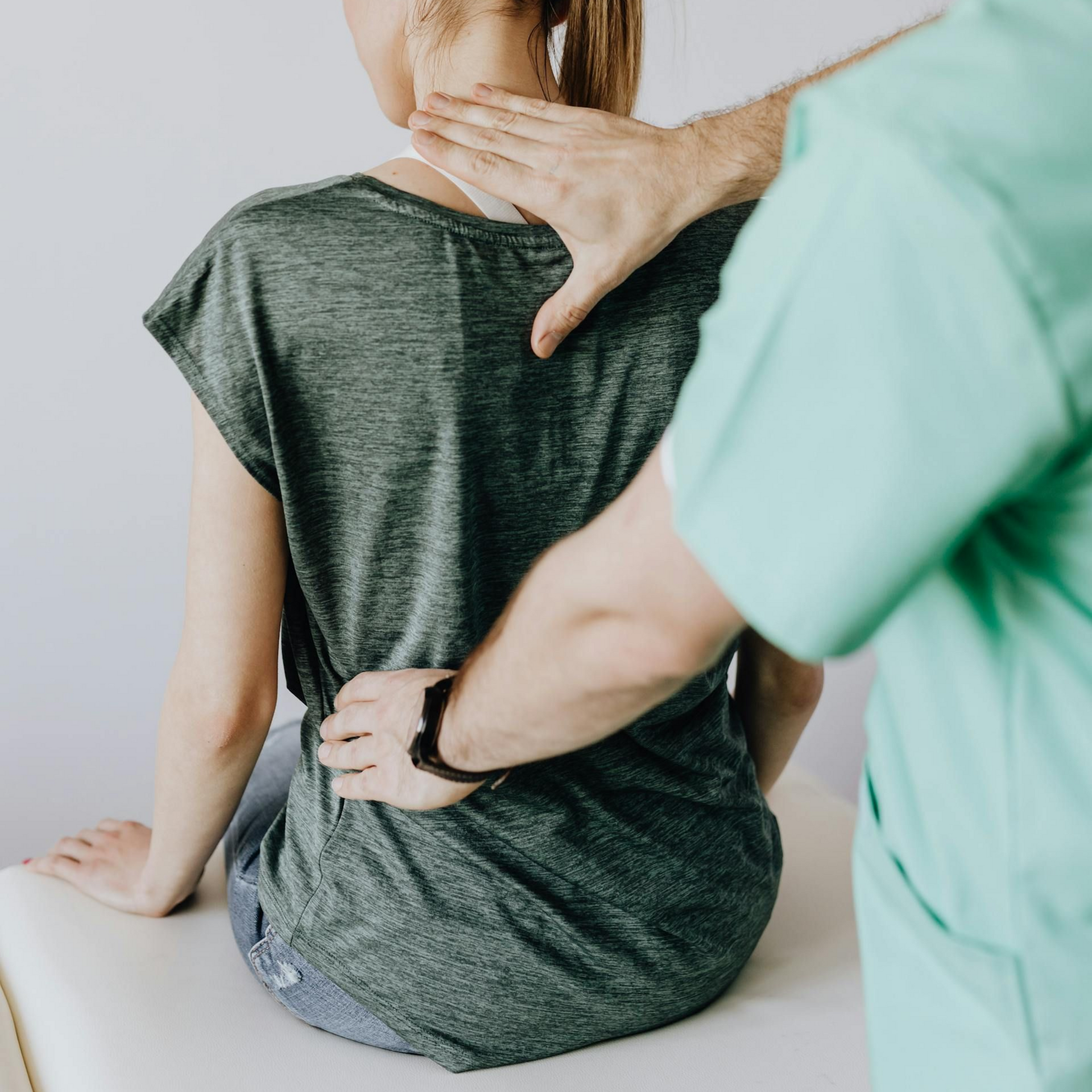 Physical therapist examining a seated patient’s back and shoulder posture