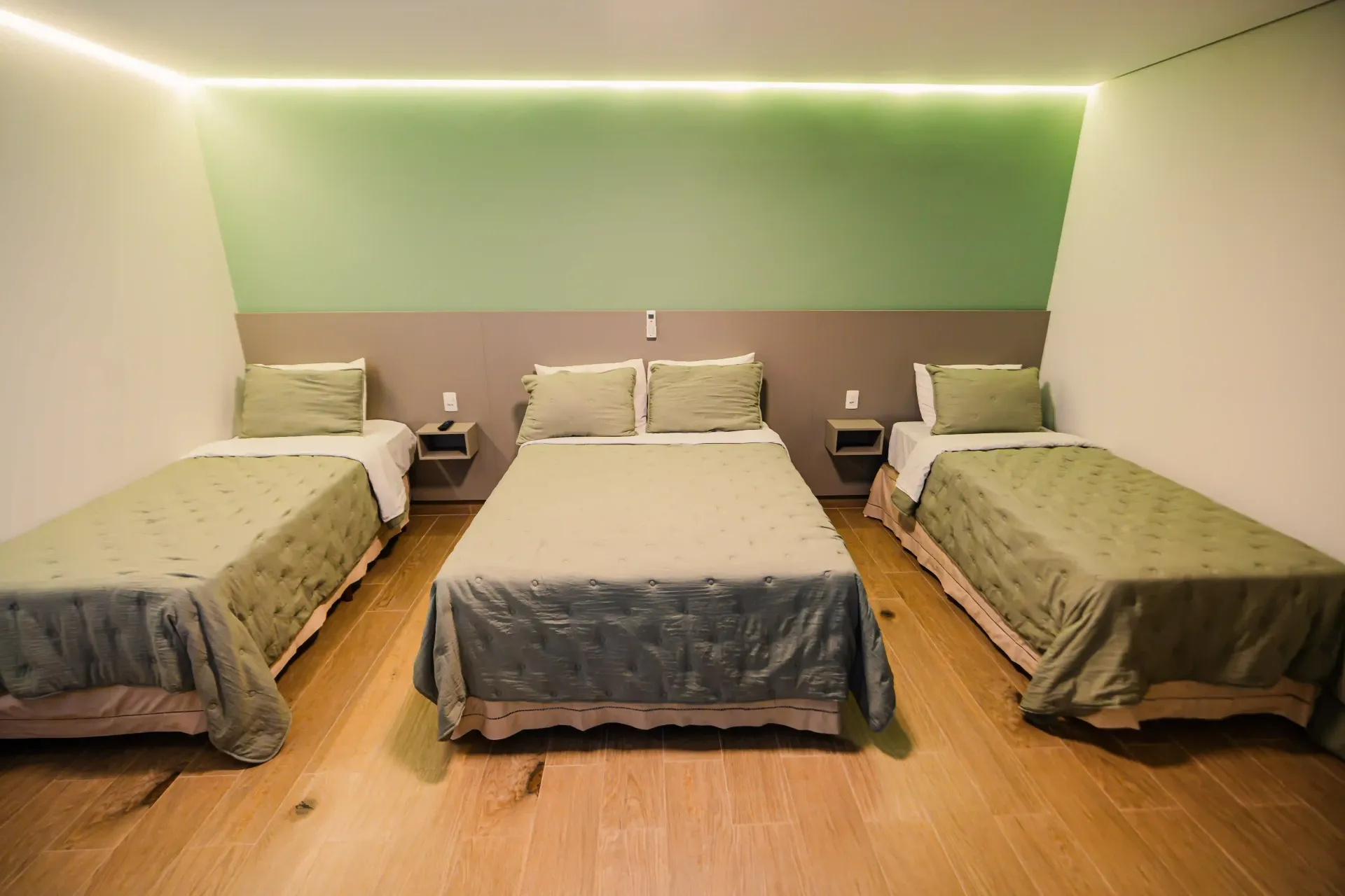 Um quarto de hotel com três camas e uma parede verde Oly Plaza Hotel