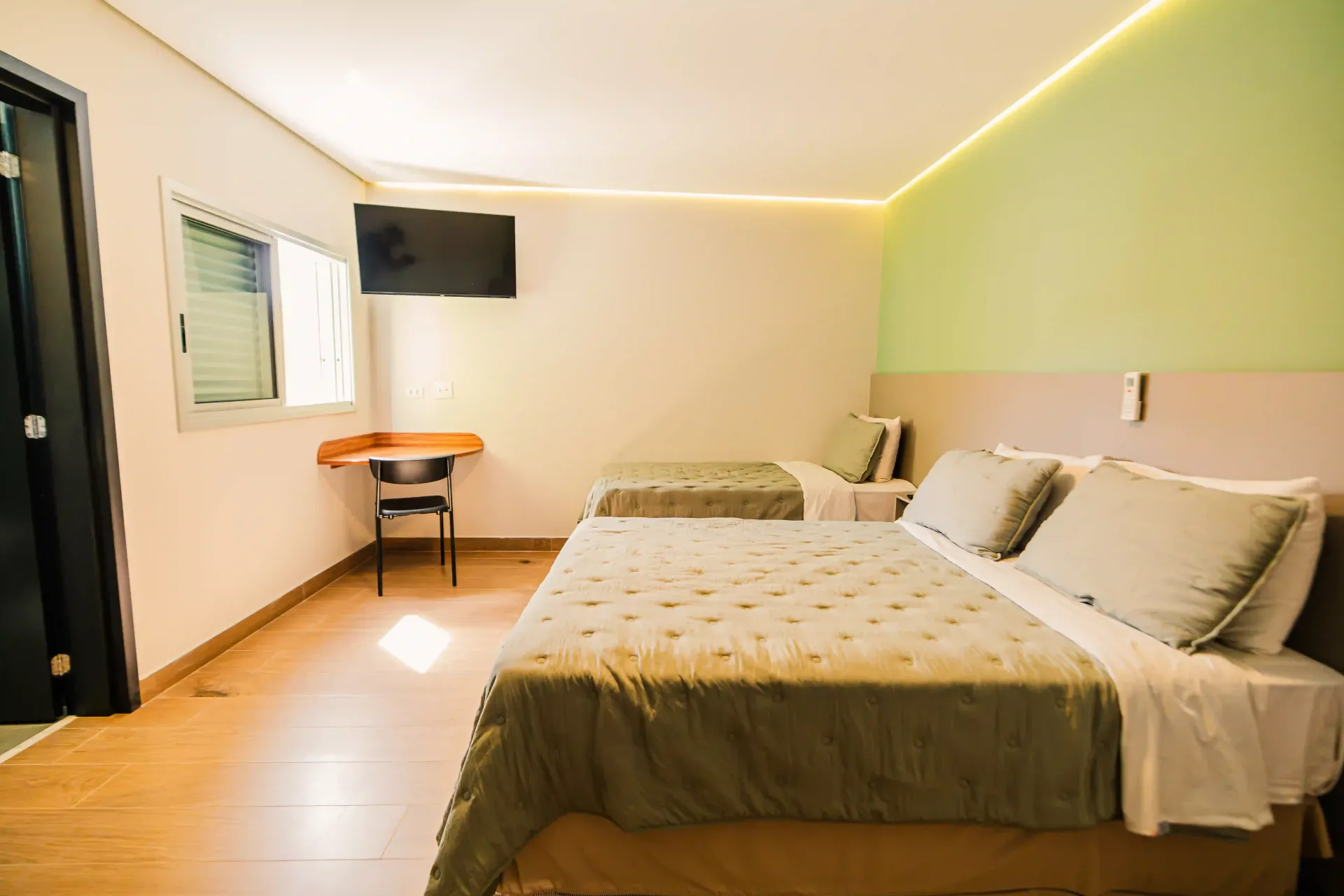 Um quarto de hotel com duas camas, uma escrivaninha e uma televisão Oly Plaza Hotel