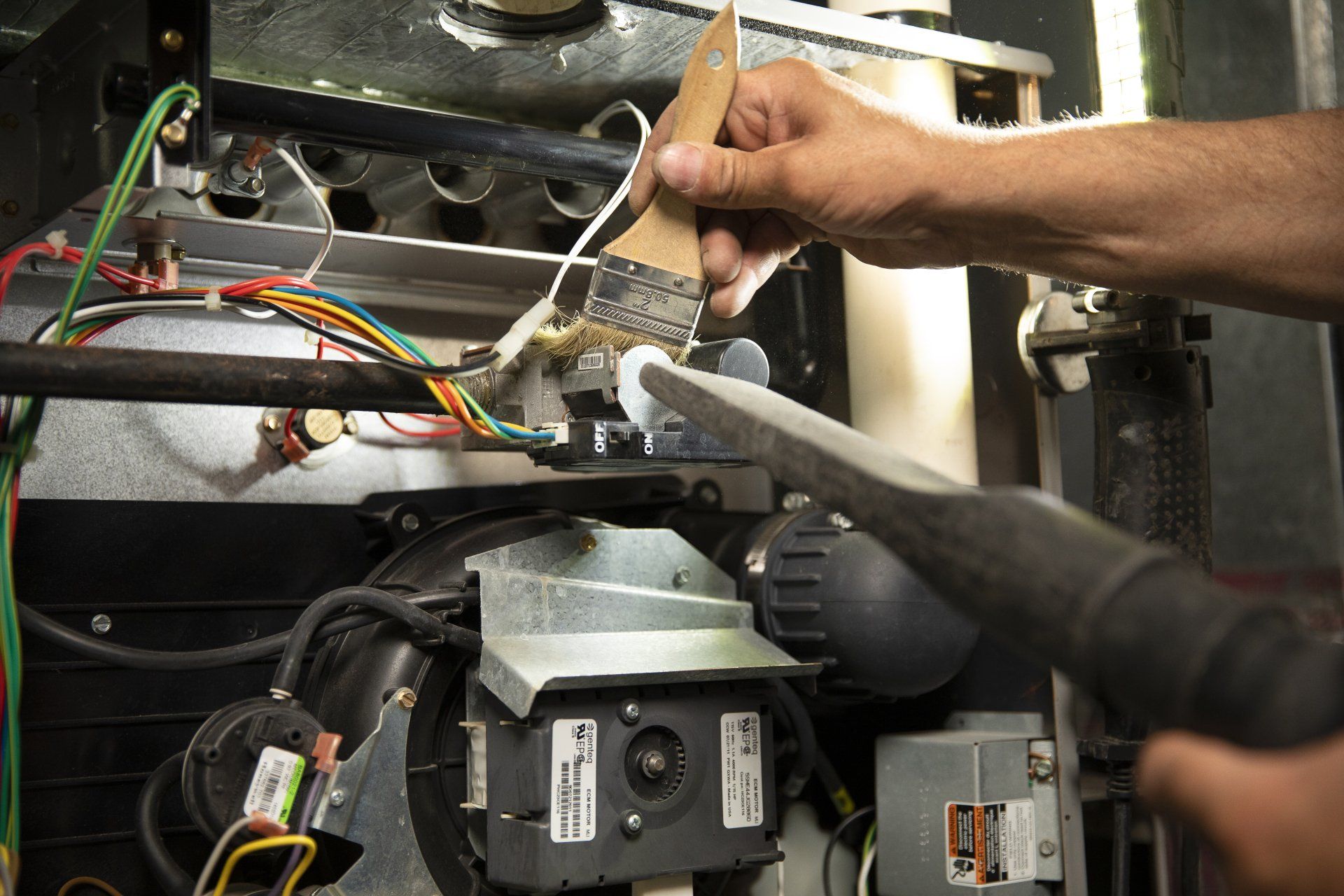 A person is cleaning a furnace with a vacuum cleaner.